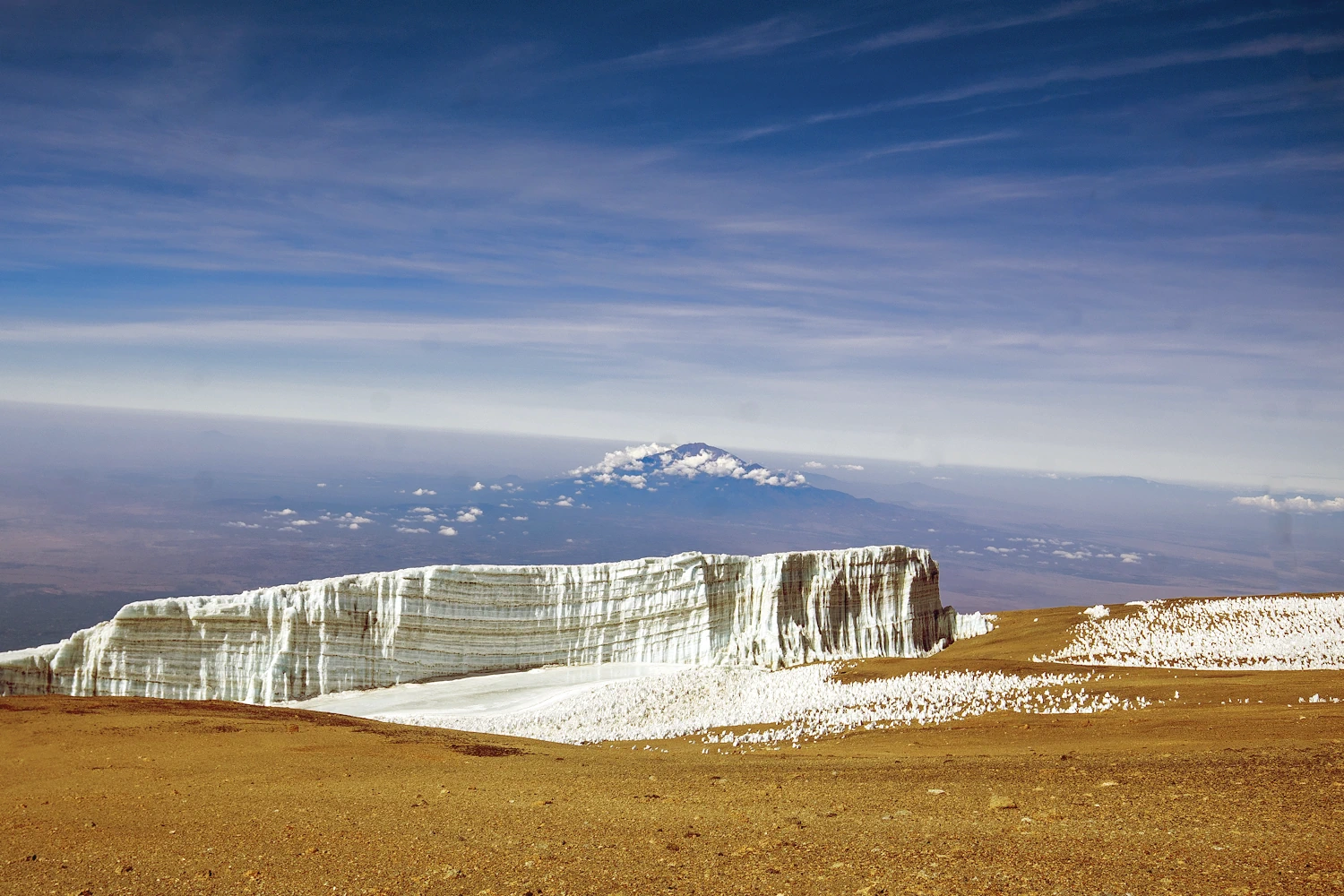 Glaciers near the summit of Mount Kilimanjaro with Mount Meru in the background, Tanzania on trekking expedition with Pure Afro Travels.